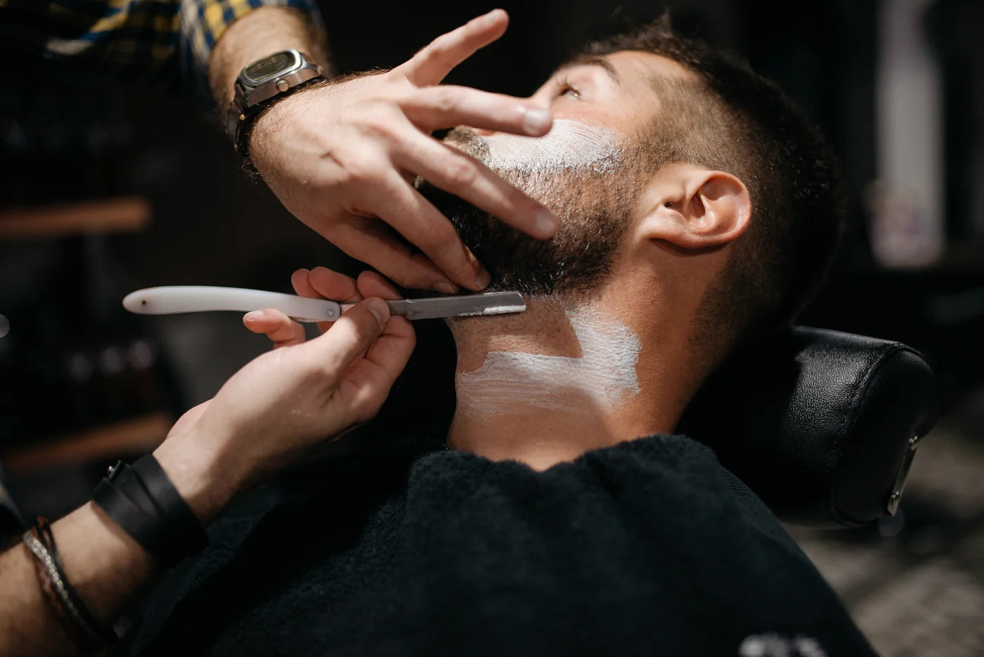 Barbier werkt met een scheermes de halslijn van een baard bij