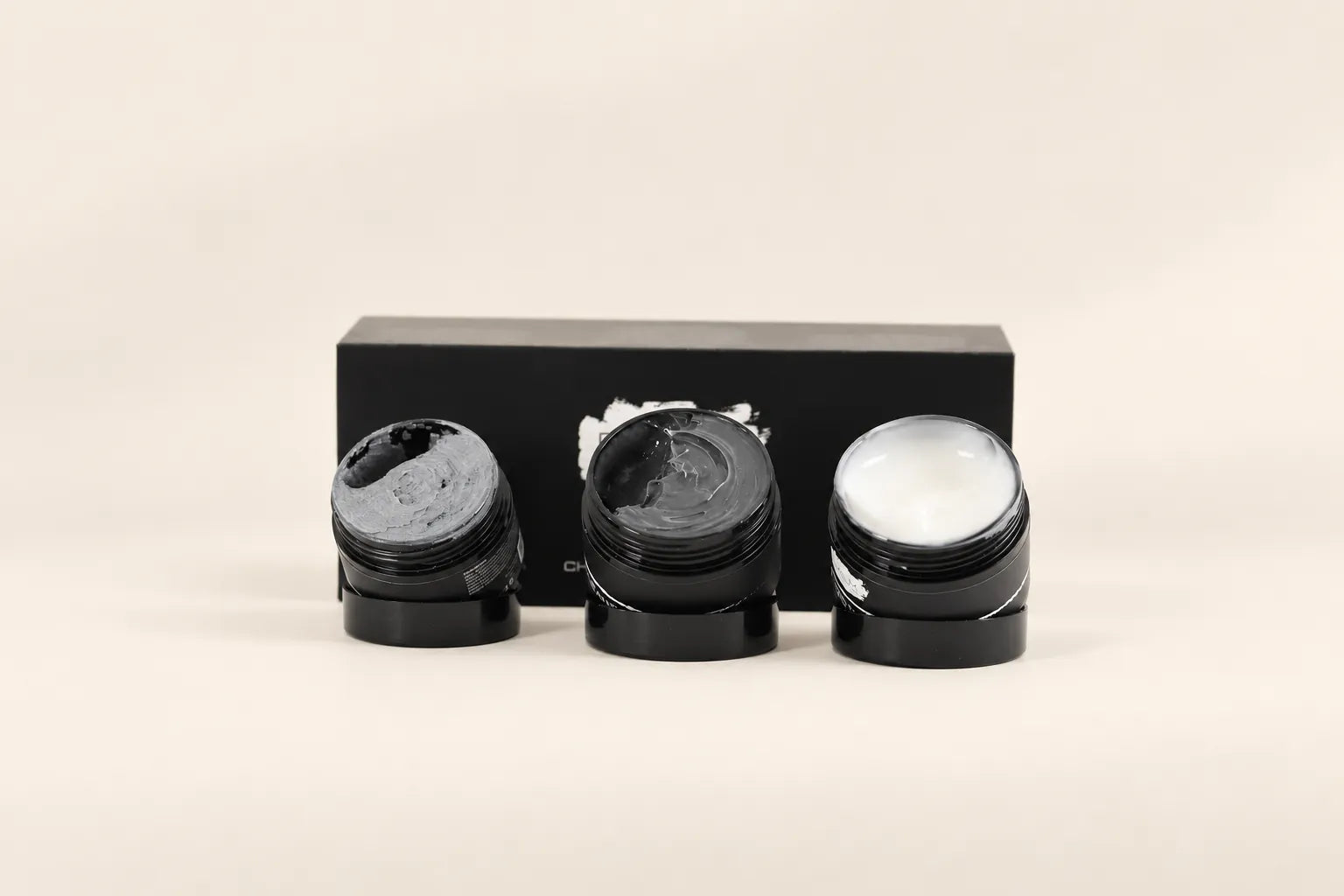 Open potten Depilation Rub, Charcoal Cleanser en gezichtscr&egrave;me met hun verschillende texturen